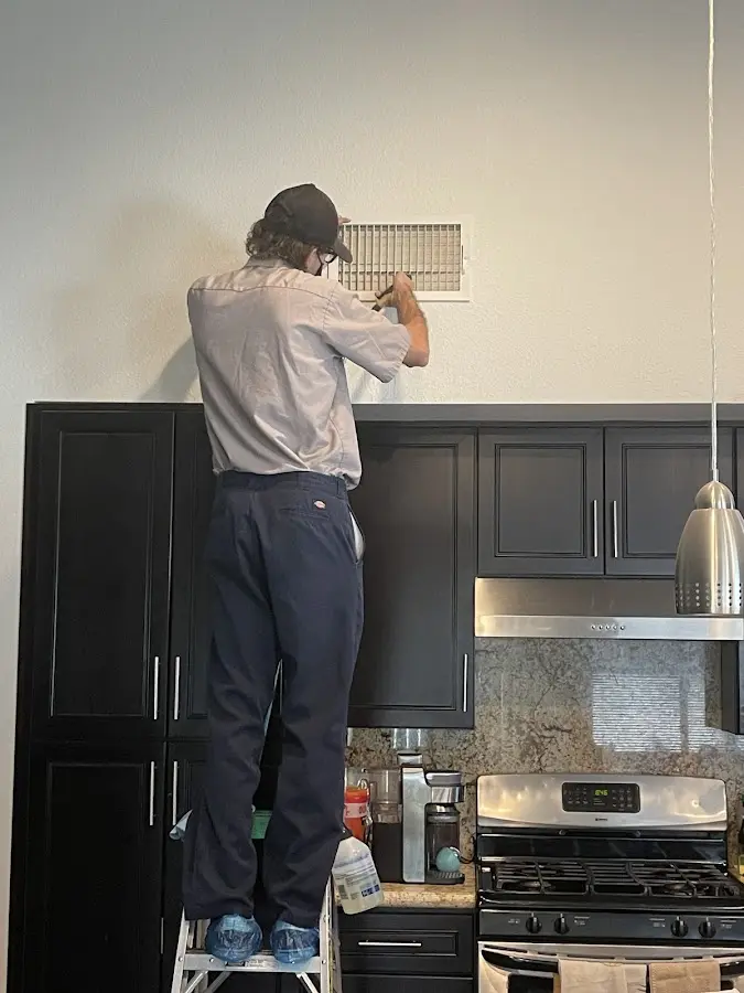 Technician inspecting an air vent during HVAC service in Highland Heights